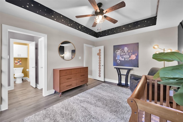 bedroom featuring baseboards, a raised ceiling, and wood finished floors