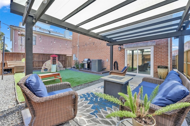 view of patio with central AC unit, an outdoor fire pit, a playground, fence, and a pergola