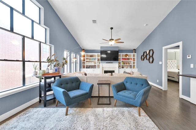 living area featuring a fireplace, visible vents, dark wood-type flooring, a ceiling fan, and baseboards