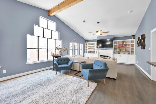 living area with beamed ceiling, a fireplace, dark wood finished floors, and a healthy amount of sunlight