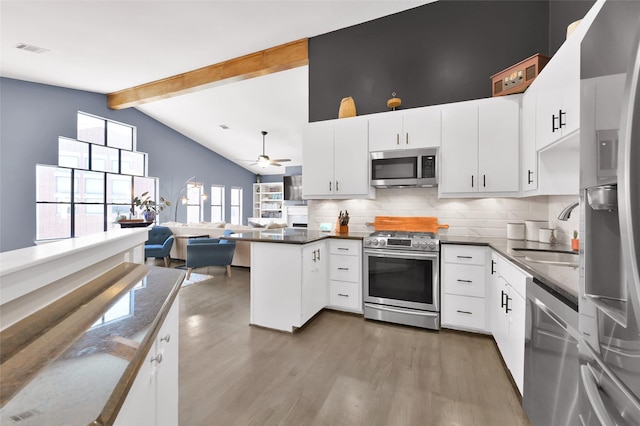 kitchen featuring white cabinets, open floor plan, a peninsula, stainless steel appliances, and a sink