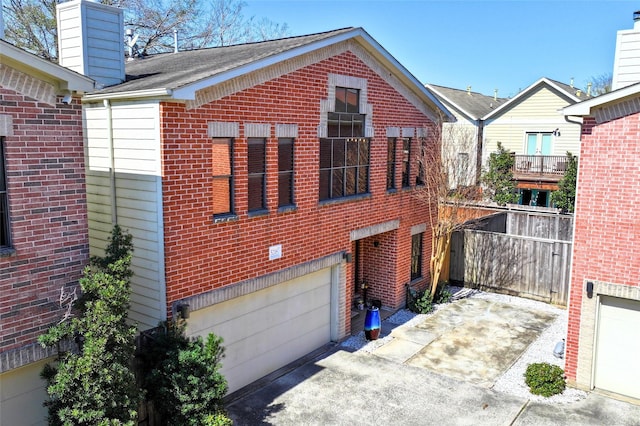 view of front of house featuring an attached garage, a chimney, concrete driveway, and brick siding