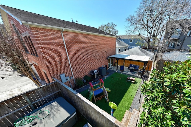 back of property featuring a lawn, a residential view, fence, a gazebo, and brick siding