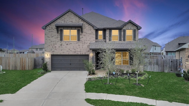 view of front facade featuring a garage, concrete driveway, fence, a yard, and brick siding