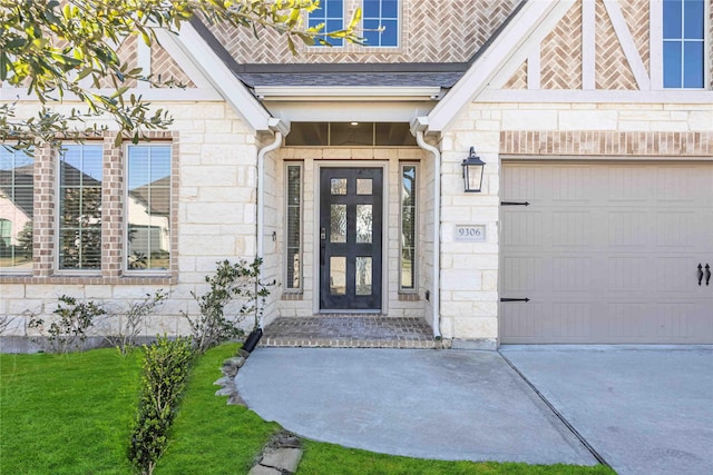 entrance to property with stone siding, a yard, roof with shingles, and an attached garage