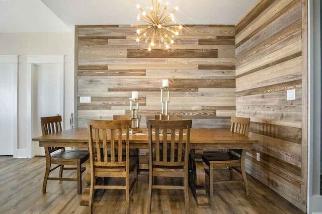 dining area with wood walls, a notable chandelier, and wood finished floors