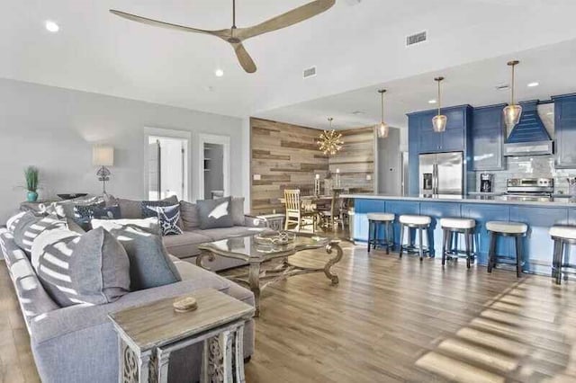 living area featuring recessed lighting, visible vents, a ceiling fan, wooden walls, and wood finished floors