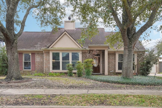 view of front of property with a shingled roof, a chimney, and brick siding