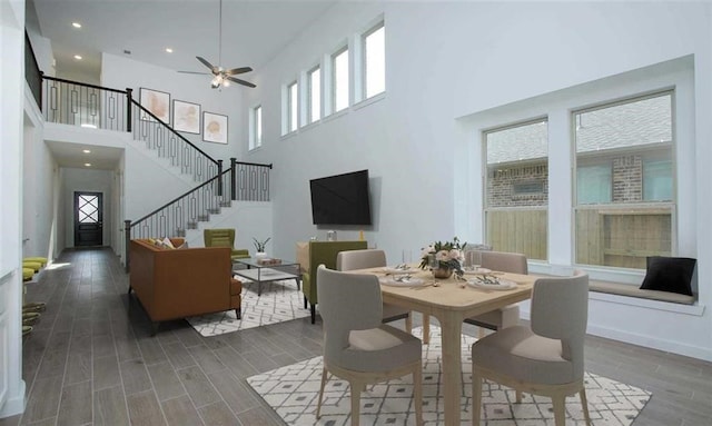 dining room featuring ceiling fan, a healthy amount of sunlight, dark wood finished floors, and stairs