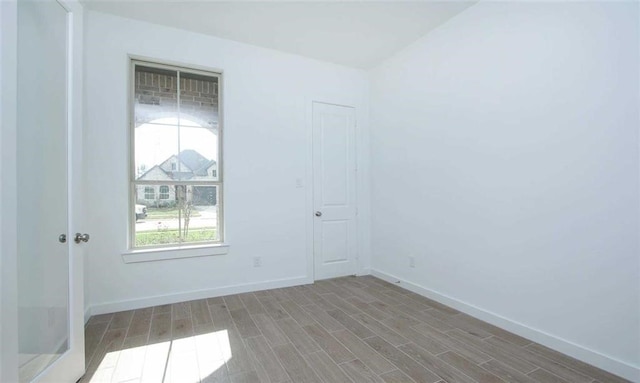 spare room featuring wood finished floors and baseboards