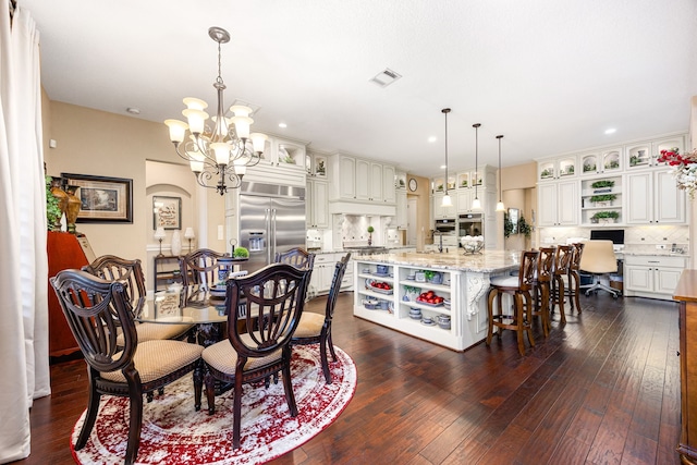 dining space featuring dark wood-style flooring, built in study area, visible vents, and an inviting chandelier