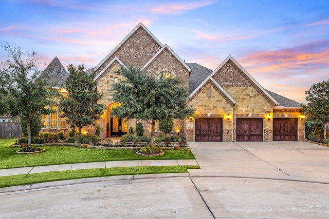 view of front facade featuring a garage, brick siding, concrete driveway, stone siding, and a lawn