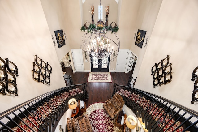 entryway featuring dark wood-style floors, a notable chandelier, a towering ceiling, baseboards, and stairs