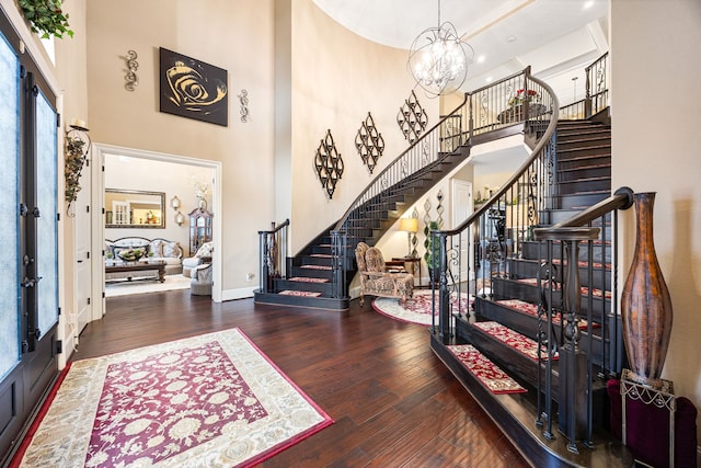 foyer with baseboards, dark wood finished floors, stairway, an inviting chandelier, and a high ceiling