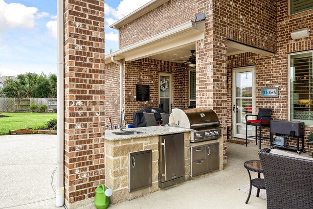 view of patio / terrace featuring an outdoor kitchen, a ceiling fan, grilling area, fence, and a sink