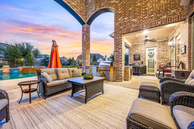 patio terrace at dusk featuring ceiling fan, an outdoor kitchen, area for grilling, outdoor lounge area, and an outdoor pool