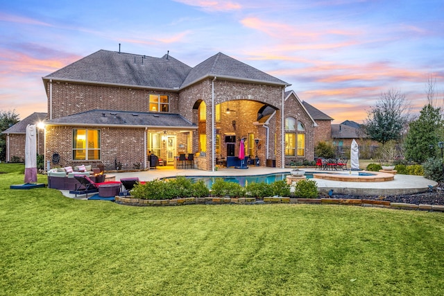 back of house at dusk featuring a patio, brick siding, outdoor lounge area, and an outdoor pool