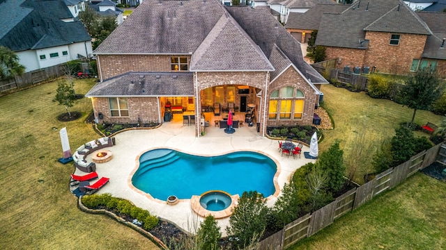 view of swimming pool featuring a yard, a patio, an outdoor bar, a pool with connected hot tub, and a fenced backyard