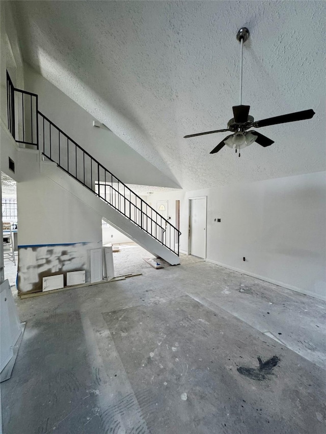 unfurnished living room featuring stairs, vaulted ceiling, and a textured ceiling