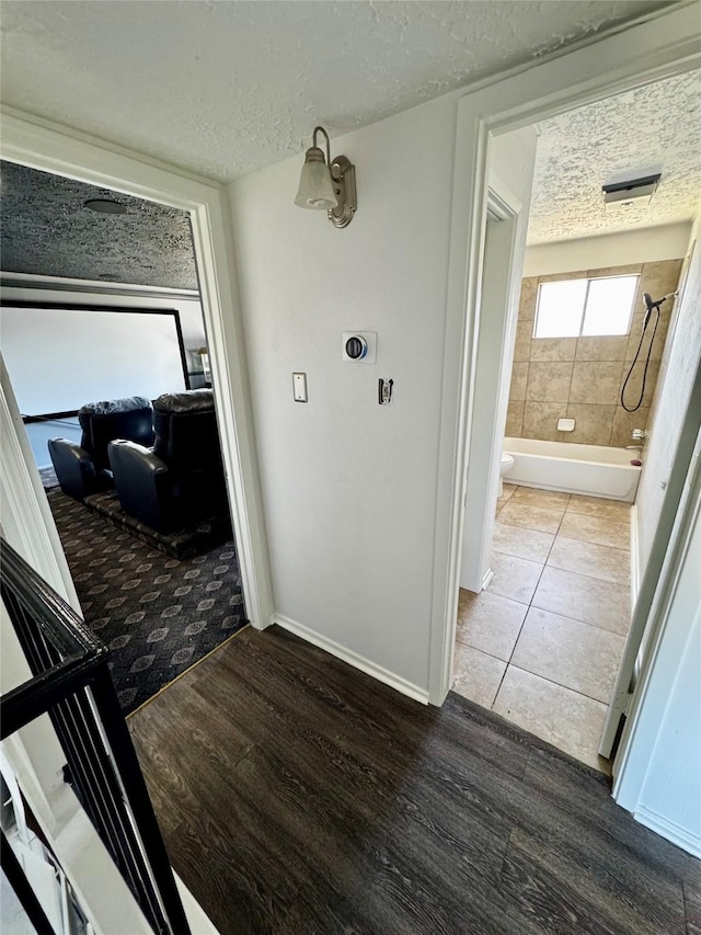 hall with a textured ceiling, baseboards, and wood finished floors