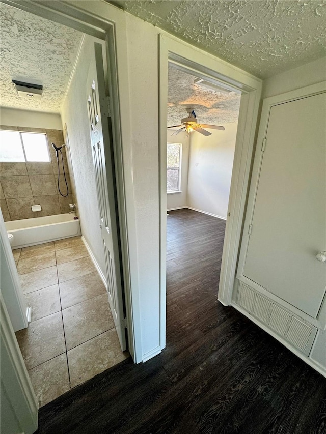 hallway featuring a textured ceiling, baseboards, and wood finished floors