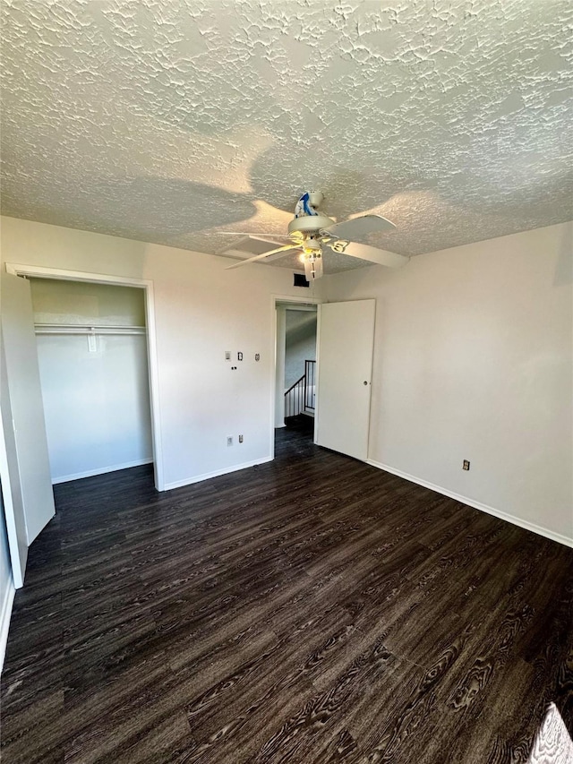 unfurnished bedroom featuring dark wood-style floors, a textured ceiling, a ceiling fan, and baseboards