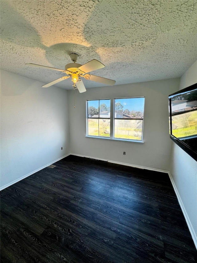 spare room featuring a textured ceiling, ceiling fan, dark wood finished floors, and baseboards