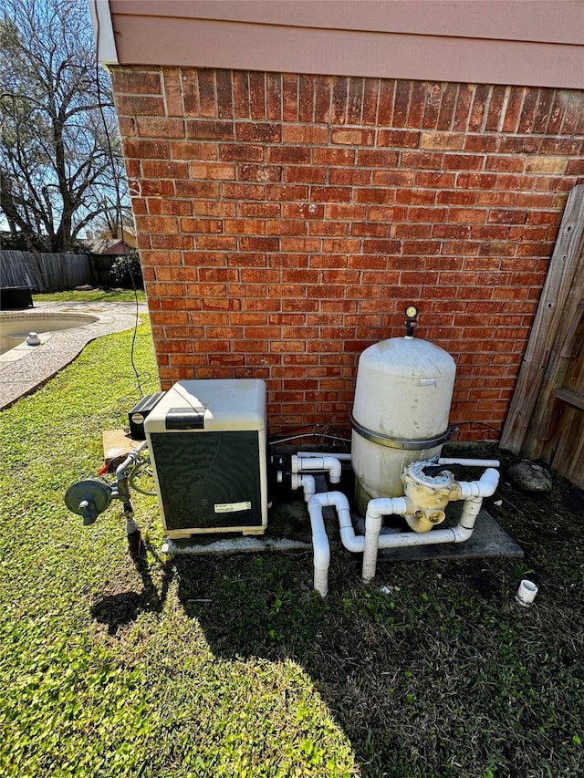 exterior details featuring fence, pump, and brick siding