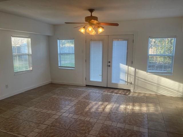 empty room featuring ceiling fan, french doors, a wealth of natural light, and baseboards