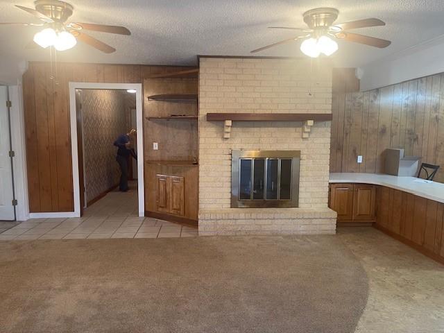 unfurnished living room featuring light colored carpet, a fireplace, a textured ceiling, and ceiling fan