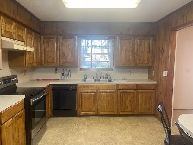 kitchen featuring black dishwasher, electric range, light countertops, under cabinet range hood, and a sink