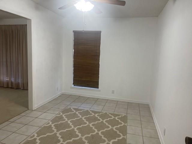 unfurnished room with light tile patterned floors, ceiling fan, and baseboards