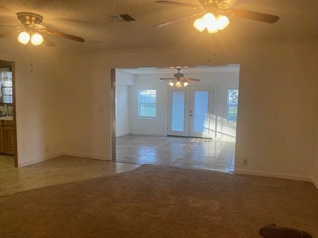 spare room featuring light carpet, a sink, visible vents, and baseboards