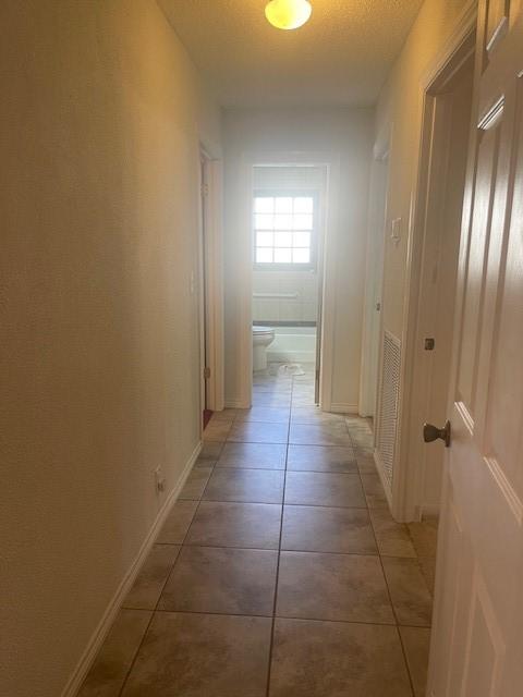 hallway featuring light tile patterned floors and baseboards