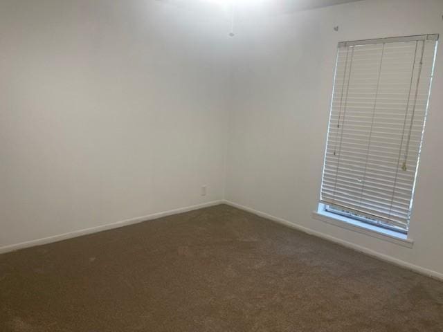 empty room with baseboards and dark carpet