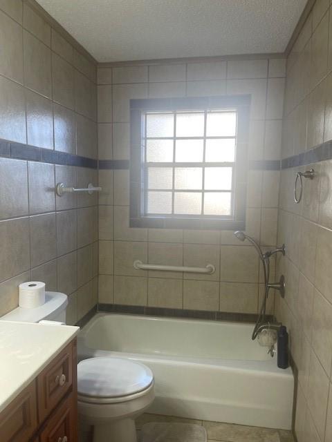 bathroom featuring bathing tub / shower combination, toilet, tile patterned floors, a textured ceiling, and vanity