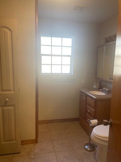 bathroom featuring toilet, tile patterned floors, vanity, and baseboards