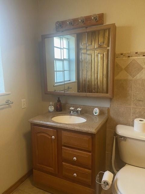 half bath featuring tile walls, vanity, toilet, and tile patterned floors