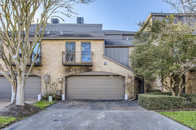 view of front of house featuring a balcony, aphalt driveway, an attached garage, board and batten siding, and brick siding