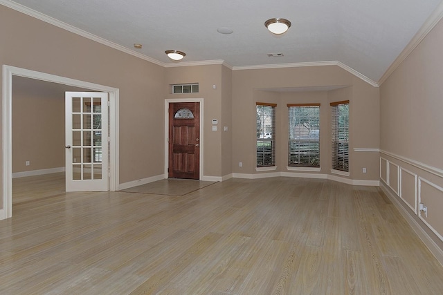 foyer entrance featuring lofted ceiling, light wood-type flooring, visible vents, and crown molding