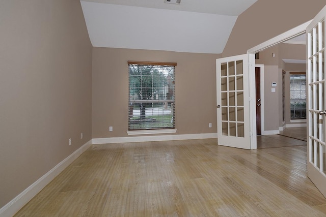 empty room featuring vaulted ceiling, french doors, light wood-style flooring, and baseboards