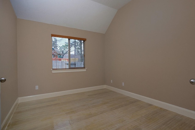 unfurnished room featuring lofted ceiling, light wood-type flooring, and baseboards