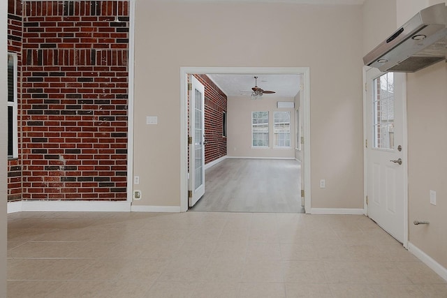 hall featuring brick wall, an accent wall, and baseboards