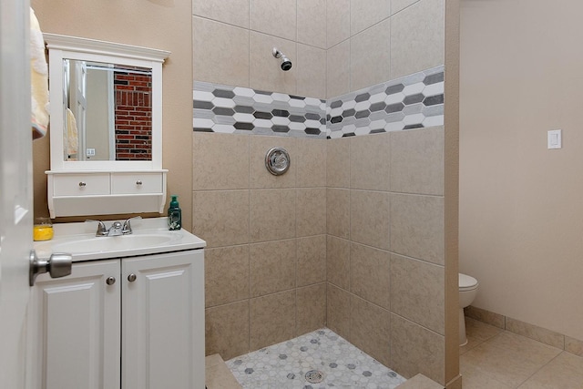 full bathroom with toilet, vanity, baseboards, tiled shower, and tile patterned floors