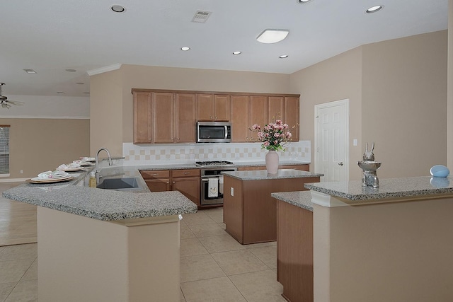 kitchen featuring a center island, stainless steel appliances, light tile patterned flooring, a sink, and a peninsula