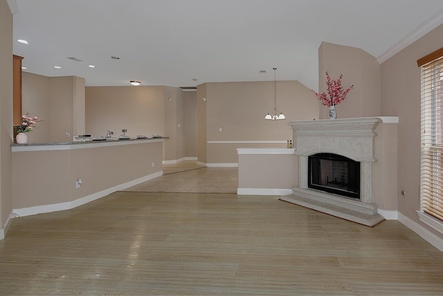 unfurnished living room with a fireplace with raised hearth, light wood finished floors, recessed lighting, and baseboards