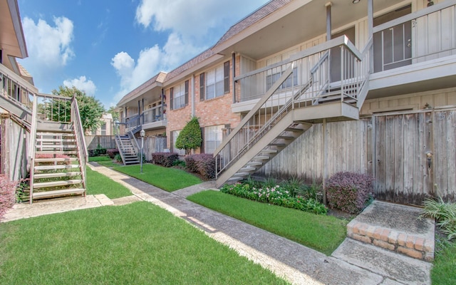 view of property's community featuring a yard, stairway, and fence