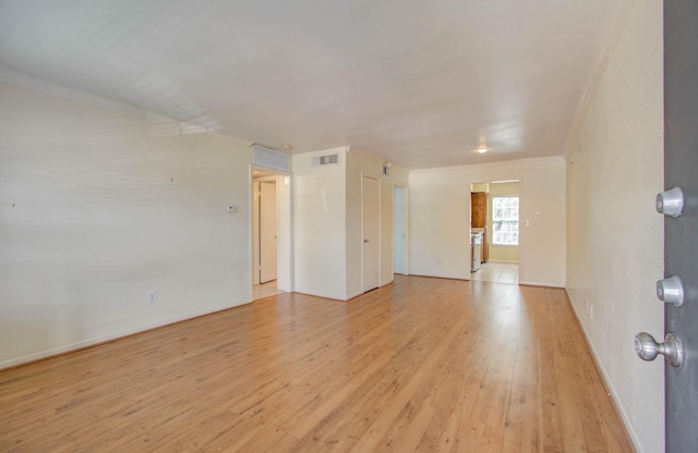 spare room with ornamental molding, baseboards, visible vents, and light wood finished floors