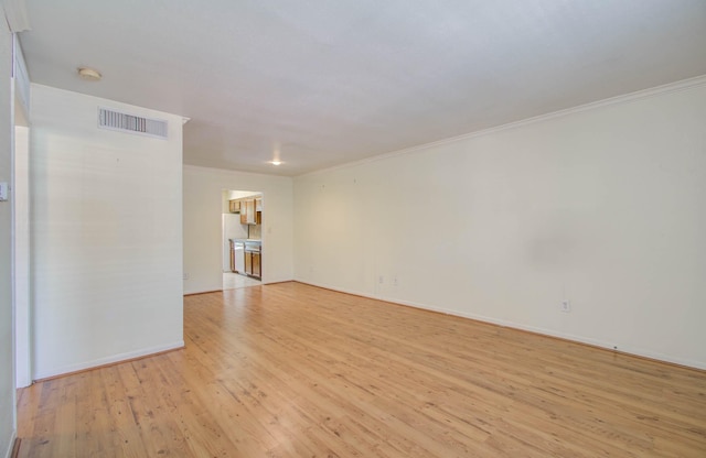 empty room with light wood-style floors, visible vents, ornamental molding, and baseboards