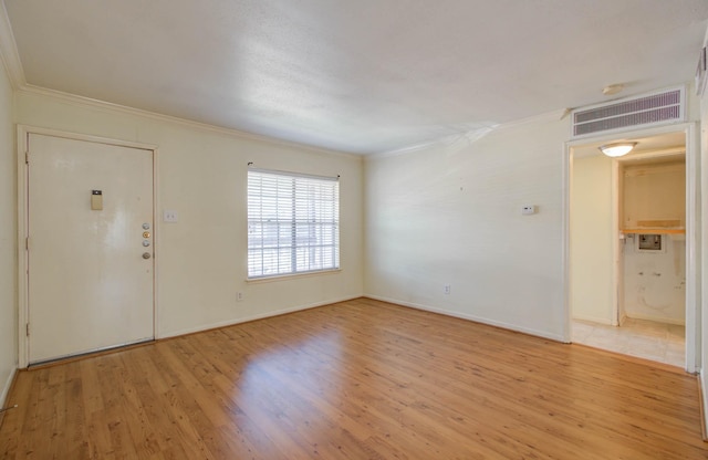 foyer featuring ornamental molding, light wood-style flooring, visible vents, and baseboards